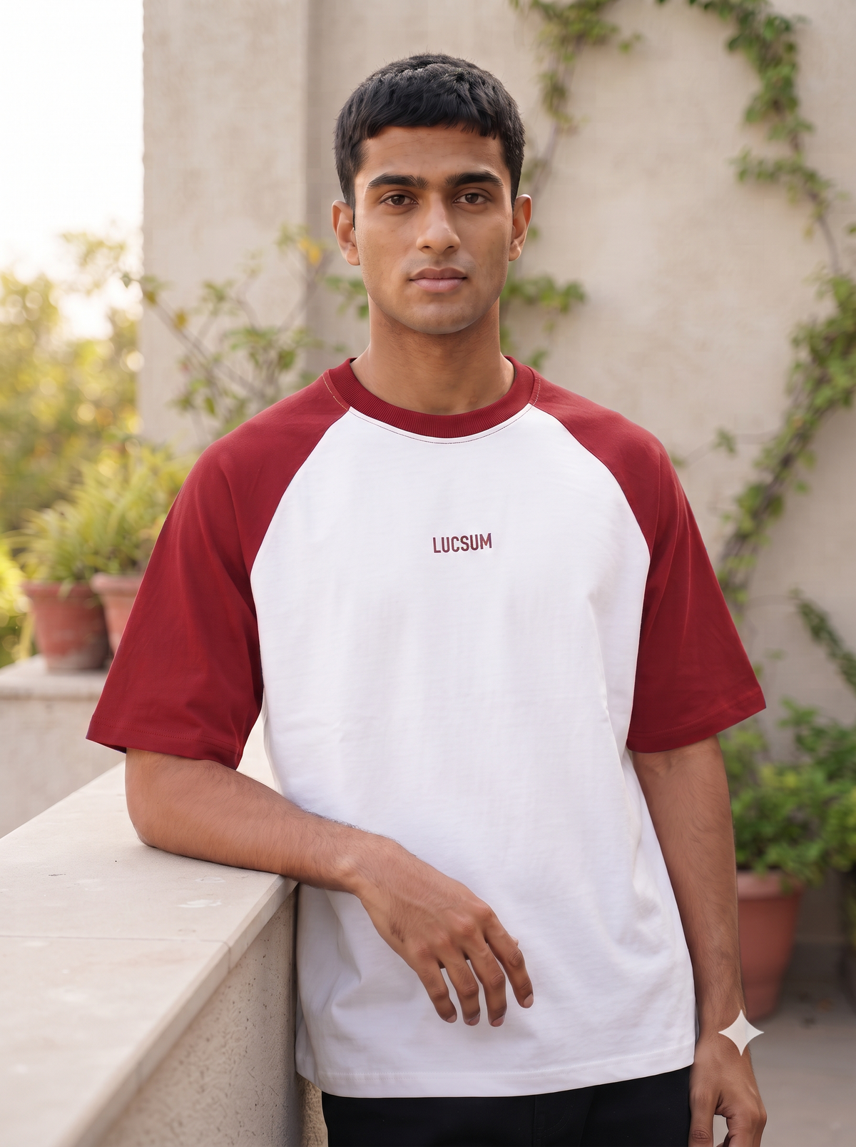 Lucsum Raglan white oversized tee with maroon sleeves worn on a sunlit terrace, lifestyle portrait