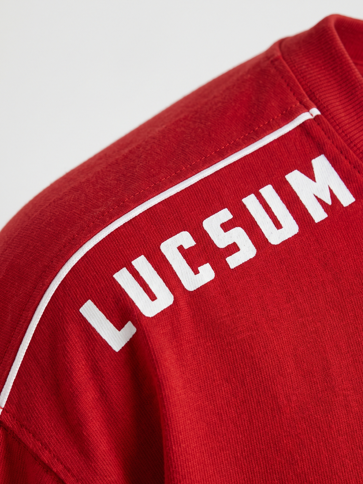Lucsum Shoulder Logo Red — Macro close-up